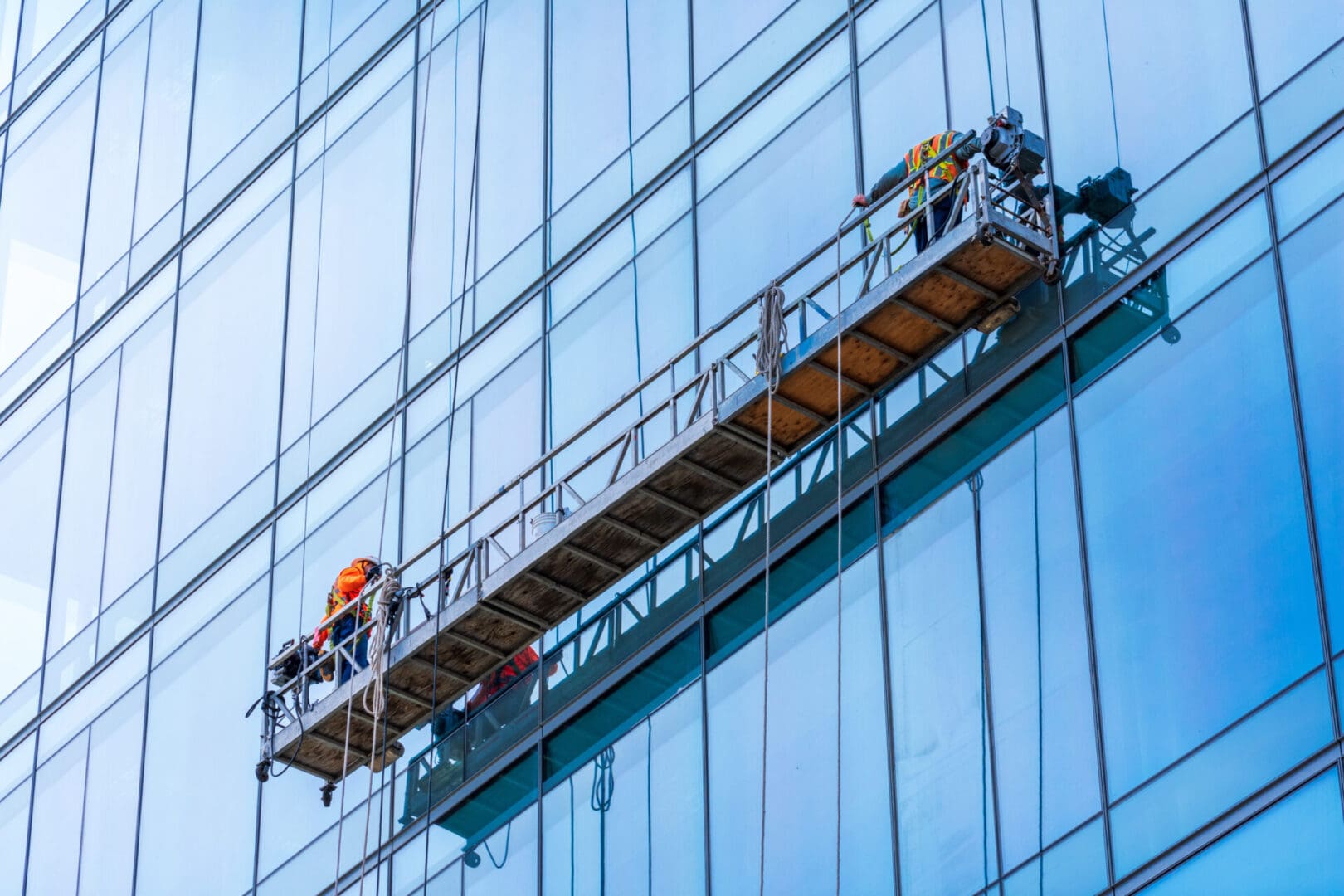 Two men on a ladder working on the side of a building.