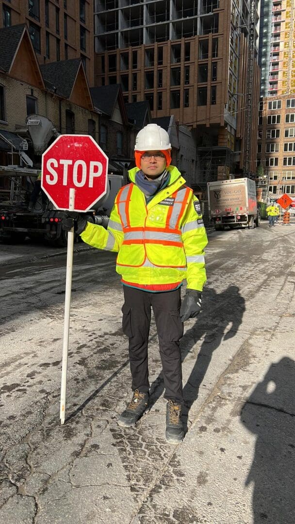 A man in yellow jacket holding up a stop sign.