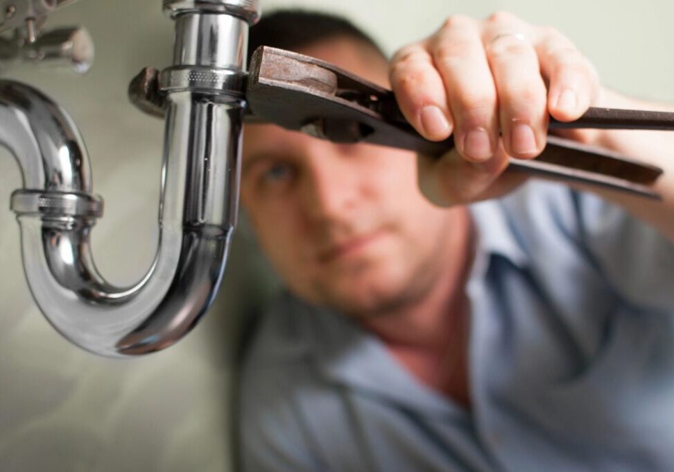 A man is fixing the faucet of his sink.